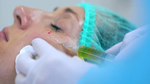 Picture of Woman Getting Botox Injection Under Her Eyes Lying with Closed Eyes in Medical Hat in