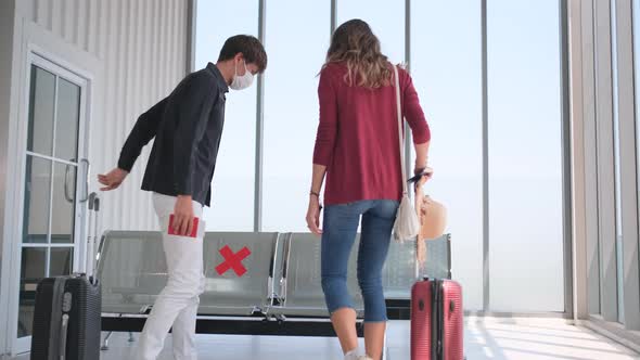 Woman with hygiene mask tell her couple man to avoid prohibit seat of waiting chair for new normal