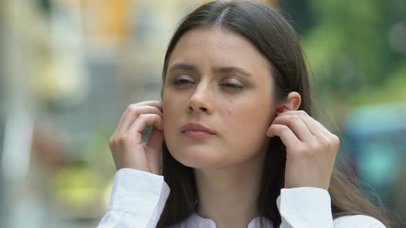 Attractive Woman Wearing Wireless Earphones Listening to Music, Enjoying Sound