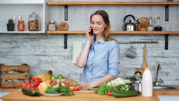 Happy Young Woman Talking Use Smartphone Cooking Food at Kitchen
