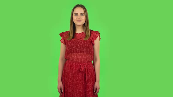 Tender Girl in Red Dress Is Coquettishly Smiling While Looking at Camera. Green Screen