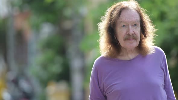 Happy Senior Man with Mustache Smiling While Thinking Outdoors