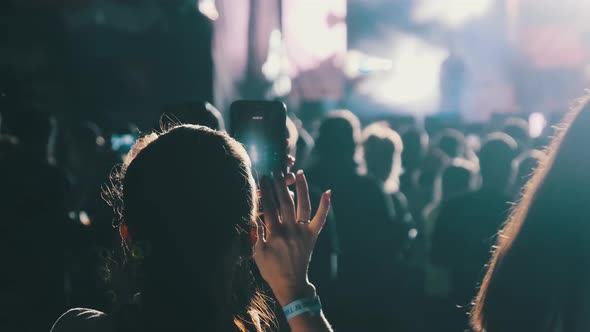 Silhouette of Woman Hands Making Video with Smartphone at Live Rock Concert. Slow Motion