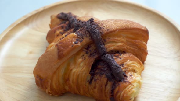 The croissants with chocolate on the wooden plate are spinning.