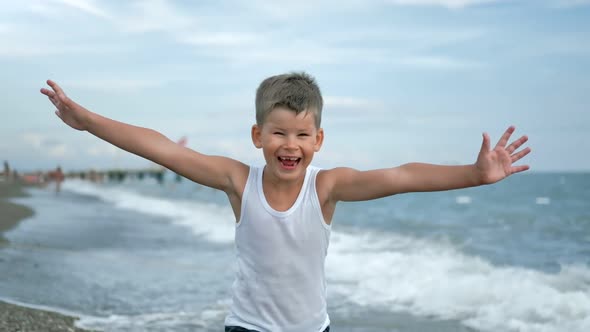 Portrait of Smiling Boy Running with Rising Hand at Coast Sea Waves Slow Motion