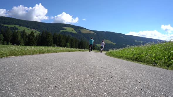 Couple Woman and Man on Electric Eco Bike Cycling Italy Dolomites Alps