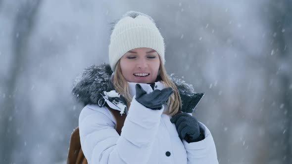 Carefree Attractive Young Woman Trying to Catch Snowflake on the Palm of Hand 6K