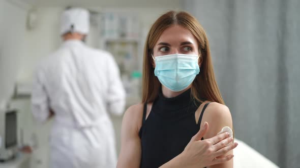 Positive Young Woman Gesturing Thumb Up After Vaccination in Clinic Indoors