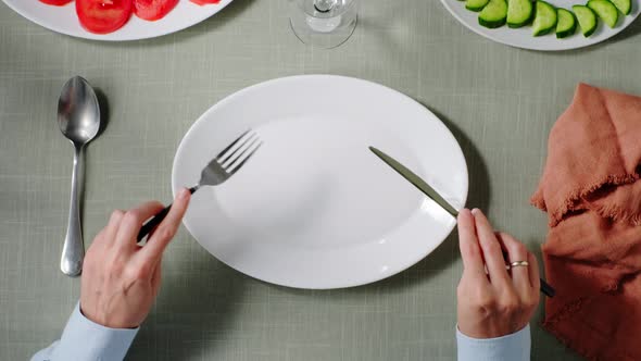 a Visitor Sits at a Table in Front of an Empty Plate in a Restaurant and Waits for an Order