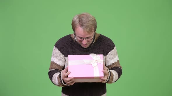 Studio Shot of Stressed Man Opening Empty Gift Box and Looking Disappointed