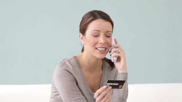 Young woman on the phone with credit card