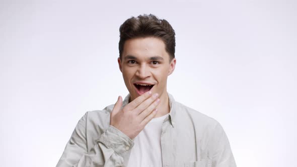 Studio Portrait of Surprised Young Guy Feeling Stunned and Amazed Spreading Hands and Touching Mouth