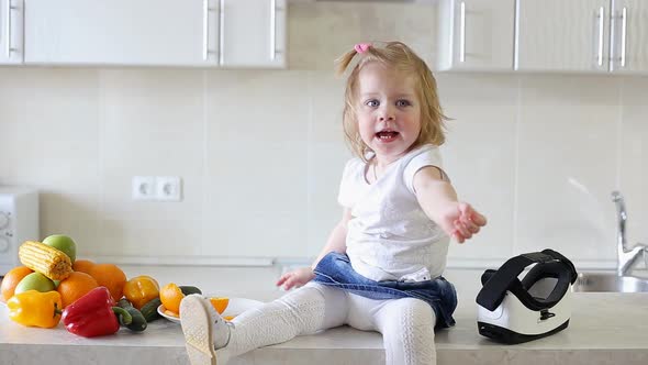 Cute Little Girl Sitting on Table in Kitchen and Throws Fruit.