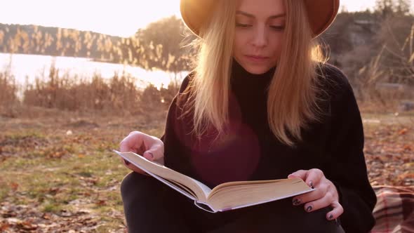 Millennial Woman Slow Motion Caucasian Blonde Woman with Beige Hat in Black Sweater Reads Book in