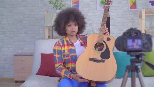 African Woman Blogger with an Afro Hairstyle with a Guitar Before the Camera