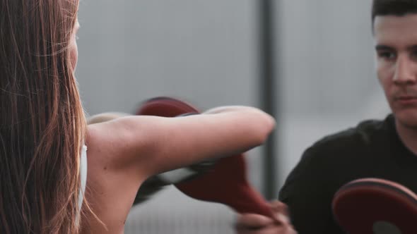 Young Woman with Long Hair in Boxer Gloves Having a Training Outdoors Punching in the Soft