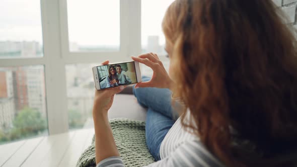 Cheerful Young Woman Is Chatting with Friends Using Smartphone Looking at Screen and Watching