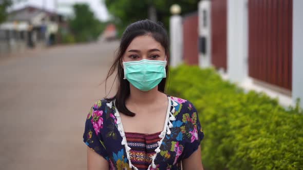 slow-motion of young woman in medical mask(surgical mask) walking outside a home