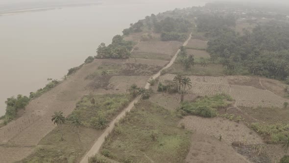 Aerial shot of coastal farmland near River Niger revealing a narrow road  to the community