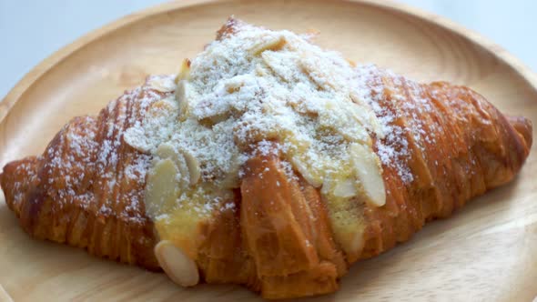 The croissants with almond and milk on the wooden plate are spinning.