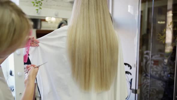 the Hairdresser Cuts the Ends of Long Blond Hair