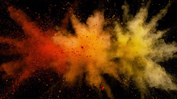 Colorful powder/particles fly after being exploded against black background. Slow Motion.