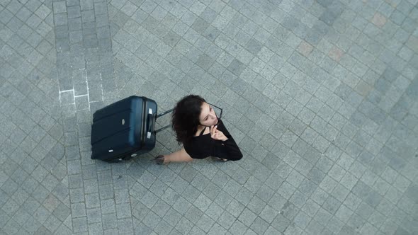 Top View Woman Walking with Suitcase Outdoor. Woman Putting Off Sunglasses