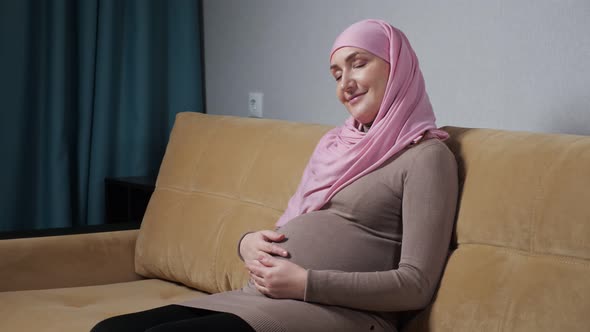 Muslim Woman Caresses Pregnant Belly and Smiles Happily