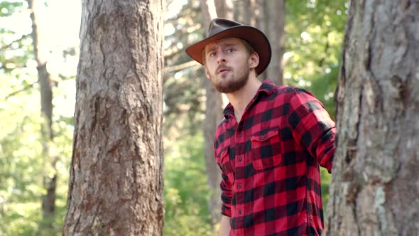 A Handsome Young Man with a Beard Carries a Tree. Stylish Young Man Posing Like Lumberjack