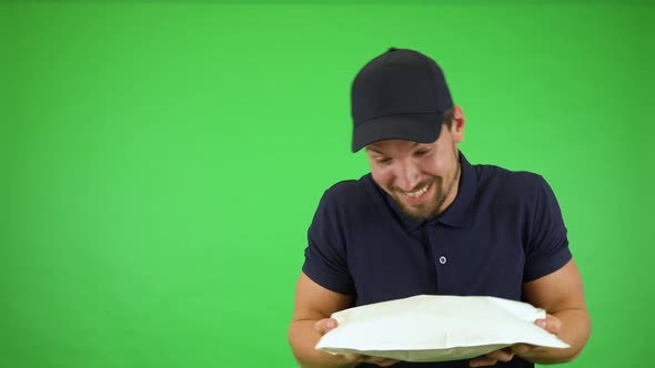 A Young Handsome Mailman Playfully Offers a Package To the Camera - Green Screen Studio