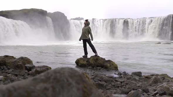 Tourist standing on stone near foamy waterfall