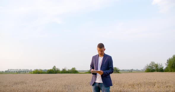 Agriculture - Farmer Using Digital Tablet During Harvesting