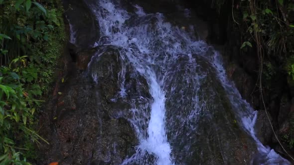 Water running downward across some rocks that are formed into perfect levels. The camera is slowly t