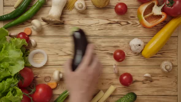 Faceless Cook Taking Eggplant From Wooden Table