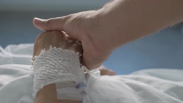 Close up medical professional holding hand of elderly Patient with iv drip, Health Care Support