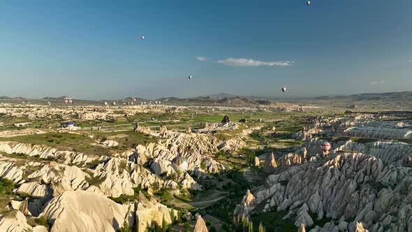 Hot air balloons fly over the mountainous landscape of Cappadocia, Turkey.