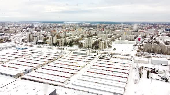 Colorful garage box doors and living district of Kaunas city during snowfall, aerial ascend view