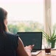 A Woman Working on a Laptop While Sitting at the Table Opposite a Window - VideoHive Item for Sale