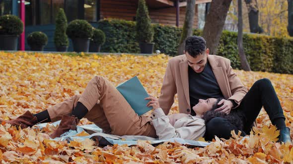 Happy Couple in Love Enthusiastically Reading Book in Autumn Park Young Spanish Man and Attractive