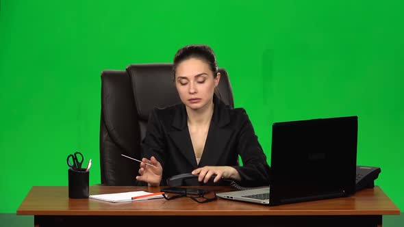 Woman at Workplace Is Working on Laptop, Talking on Two Phones and Sawing Nails. Green Screen. Slow