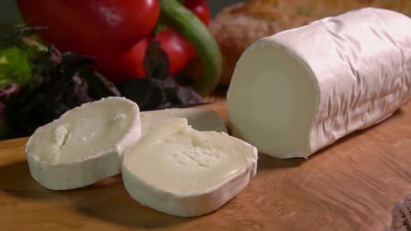 A Large Round Piece of Sainte Maure De Touraine Goat Cheese Falls on a Board