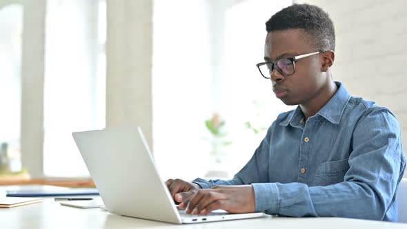 Young African Man with Laptop Shaking Head in Denial No Sign