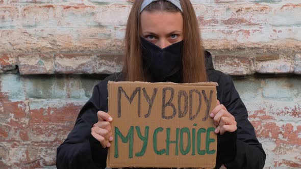 Young woman protester holds cardboard MY BODY MY CHOICE sign Girl Feminist protesting equal rights