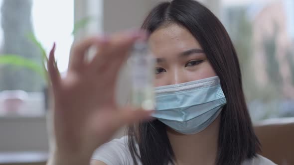 Rack Focus From Asian Woman in Covid Face Mask Stretching Vial to Covid19 Vaccine in Female Hand