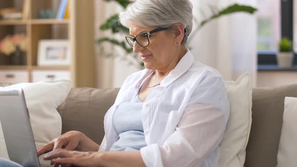 Happy Senior Woman Typing on Laptop at Home