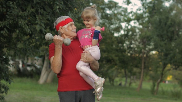 Granddaughter and Grandfather Doing Fitness Exercises with Dumbbells. Senior Man with Child Kid Girl