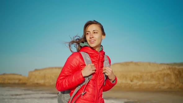 Slow Motion Portrait of Happy Smiling and Joyful Young Woman Hiker in Red Jacket Walking on Salty