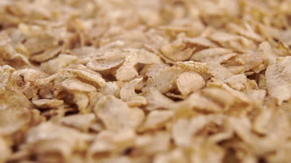 Dry uncooked cereal spelt flakes fall on a pile