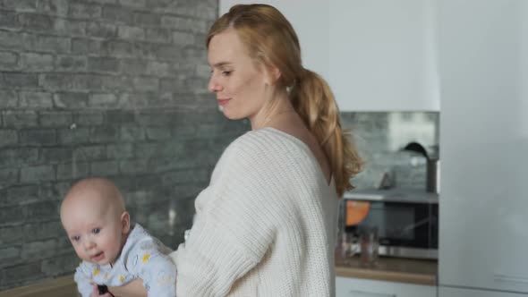 baby flies in mom's arms in the kitchen