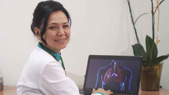 Mature Female Doctor Examining Lungs Scan on Her Laptop at the Clinic